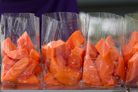 Thailand street food ripe papaya in plastic bag ready for sale,Selective focus.Fresh ripe papaya fruits sliced in a street market. / ripe papaya in plastic bag ,Thailand street market.の写真素材