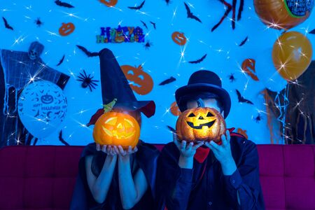 Wizard man and witch woman holding pumpkin close face in sparkle background - Asian young people in halloween party conceptの写真素材