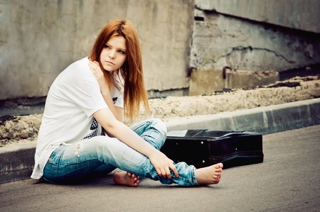 Beautiful young girl sitting on asphaltの写真素材