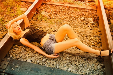 Beautiful young girl lying on the railsの写真素材