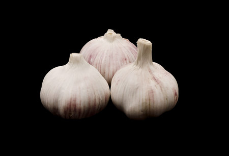 Closeup of three cloves of garlic. Isolated on black background