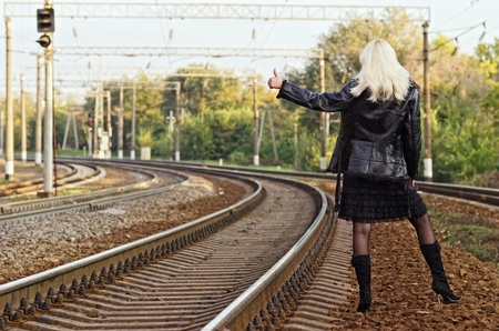 Beautiful young girl is hitch hiking on a railroadの写真素材