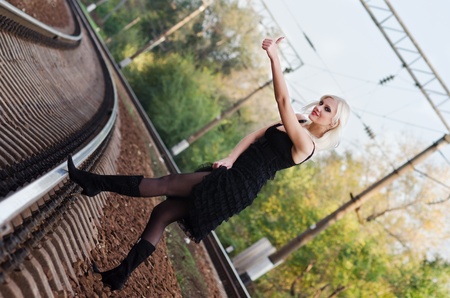 Sexy young girl in black dress is hitchhiking on a railroadの写真素材