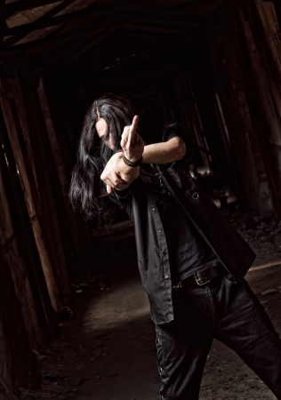 Portrait of long-haired young man making offensive gesture  middle finger の写真素材