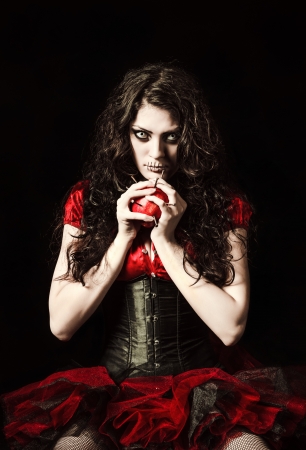 Horror shot  the strange scary girl with mouth sewn shut holds apple studded with nailsの写真素材