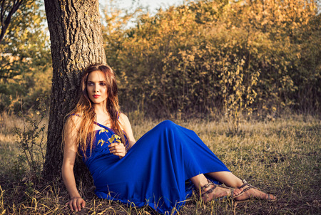 Beautiful young woman sitting under the tree  Sunset timeの写真素材