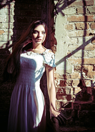 Dramatic portrait of a beautiful young woman in white dressの写真素材