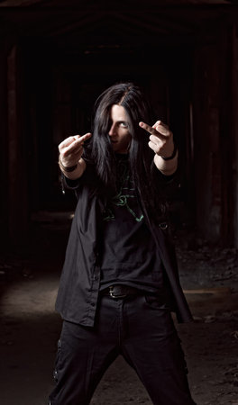 Portrait of long-haired young man making offensive gesture  middle fingers 
