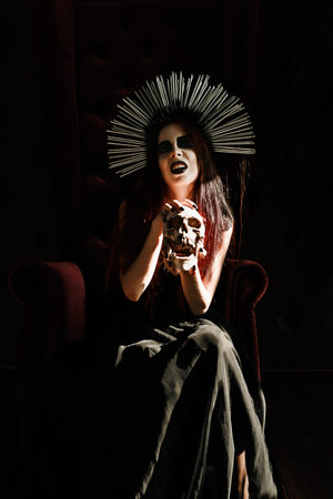 Horror photo: a scary young witch holds the skullの写真素材