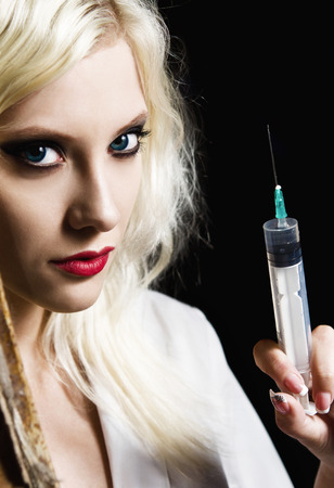 Beautiful young girl in the image of nurse with syringe in hand. Closeupの写真素材