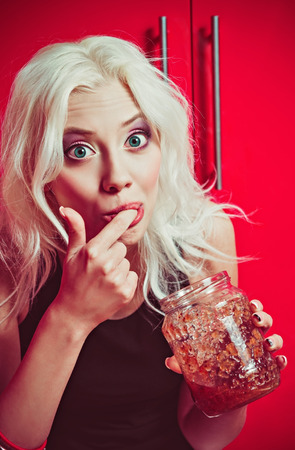 Closeup portrait of a beautiful blonde girl eating jamの写真素材