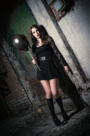 A strange young girl holding black balloonの写真素材