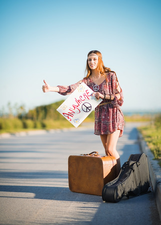 Portrait of a lovely young hippie girl hitchhiking on the roadの写真素材