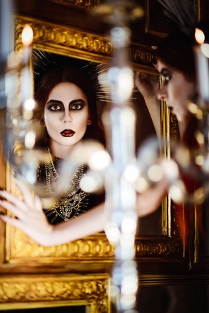 Gothic fashion: mysterious beautiful young woman looking into the mirrorの写真素材