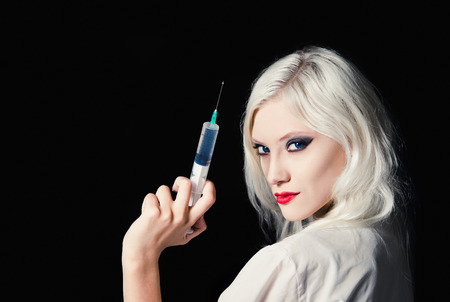 Smiling beautiful young girl in the image of nurse with syringe in hand. Closeupの写真素材
