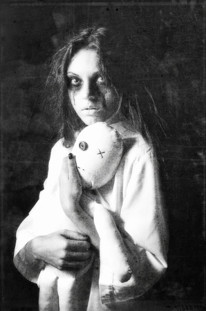Horror style shot: the mysterious ghost girl with moppet doll in hands. Grunge texture effectの写真素材
