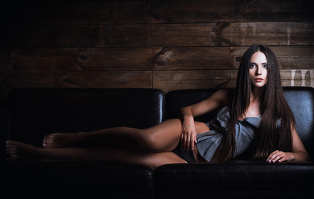 A beautiful young woman in panties and shirt lying on sofaの写真素材
