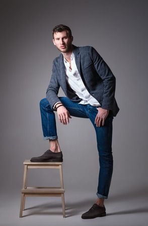 Studio fashion shot: portrait of a handsome young man wearing jeans, shirt and jacketの写真素材