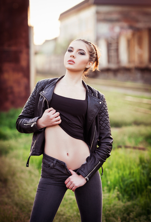 Outdoor fashion shot: a beautiful young girl in black jacket, shirt and jeansの写真素材