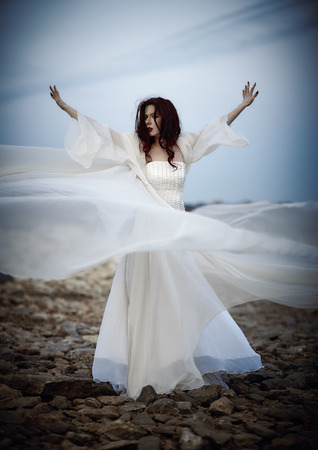 Outdoor portrait of a beautiful sad young woman in white dressの写真素材