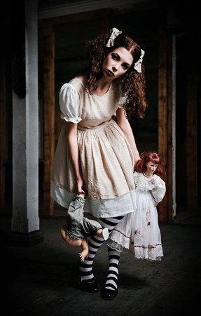The strange scary girl with dolls in handsの写真素材