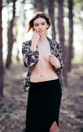Beautiful sexy young woman stands among the treesの写真素材
