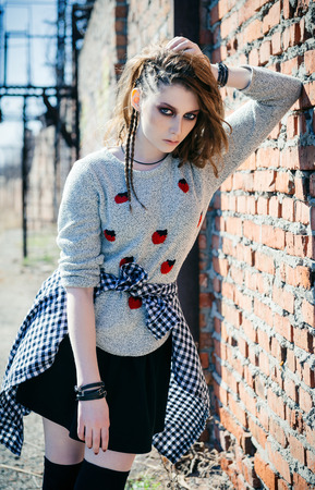 Lovely sad grunge (rock) girl standing near the wallの写真素材