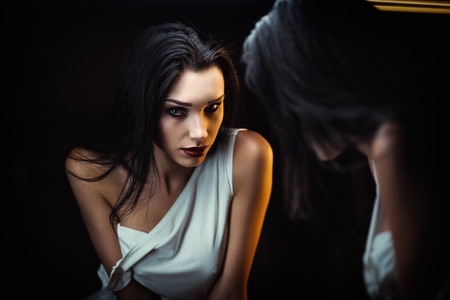 Closeup portrait of seductive young woman looking into the mirrorの写真素材