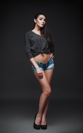 Studio fashion shot: portrait of the beautiful young woman in denim shorts and blouse. Model testの写真素材