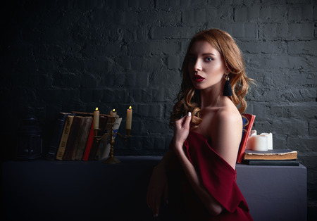 Dramatic portrait of the sexy lovely young woman in lowered red dressの写真素材