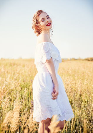 Portrait of sweet young smiling girl wearing white dress in a meadowの写真素材