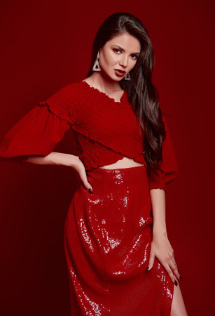 Studio fashion: adorable young woman dressed in red skirt and blouse. Portrait of charming beautiful girlの写真素材