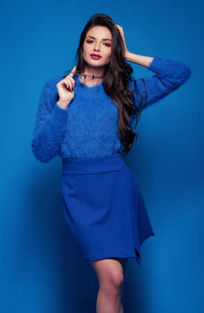 Studio fashion: sweet smiling young woman dressed in blue skirt and sweater. Portrait of gorgeous girlの写真素材