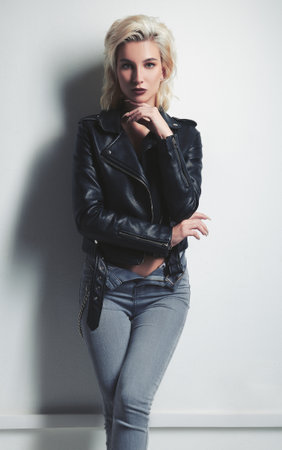 Studio fashion: pretty young woman in black leather jacket and denim. Cool informal (rock) girl against white wallの写真素材