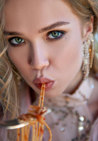 Lovely girl eating pasta (spaghetti). Close-up portrait of a beautiful young womanの写真素材