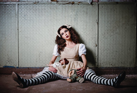 Weird girl with dolls sitting in the abandoned placeの写真素材