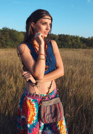 Outdoor portrait of the smiling lovely young boho (hippie) girl in meadow at sunset time. film grain addedの写真素材