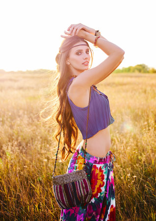 Outdoor portrait of the smiling beautiful young boho (hippie) girl in the fieldの写真素材