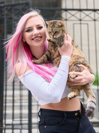 Cheerful cute young woman holding sweet cat. Outdoor portrait of smiling pretty girlの写真素材