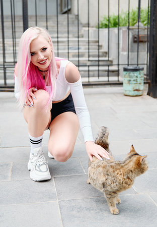 Beautiful young woman with cat. Outdoor portrait of an attractive smiling girlの写真素材