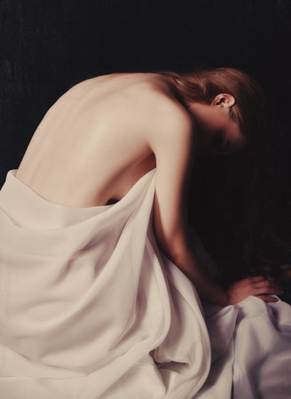 Tragic portrait of the beautiful young sad girl against black background. Sorrowful woman among the...