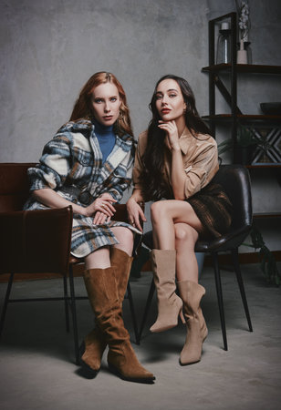 Retro fashion: two beautiful young women sit on chairs. Vintage portrait of lovely girls in seventies styleの写真素材