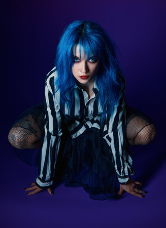 Studio portrait of goth girl. Beautiful blue-haired gothic lady in striped shirt, black skirt and pantyhose.の写真素材