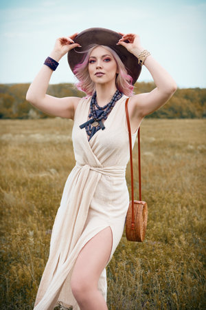 Outdoor fashion: portrait of the beautiful young boho (hippie) girl in field. Cute hippy woman in meadowの写真素材