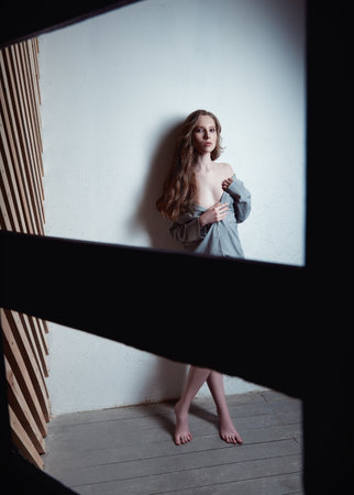 Studio fashion shot: the beautiful sexy young girl in jacket and panties, topless. Charming seductive woman standing at the wall Shooting through the ladderの写真素材