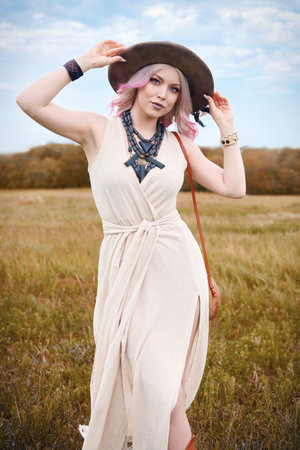 Outdoor fashion: portrait of the sweet young boho (hippie) girl in field. Cute hippy woman in meadowの写真素材