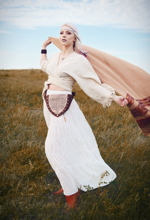 Outdoor fashion: portrait of the sweet young boho (hippie) girl in field. Cute hippy woman in meadowの写真素材