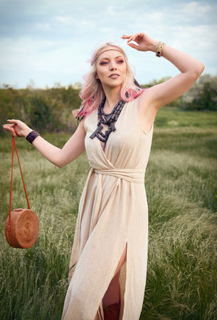 Outdoor fashion: portrait of the pretty young boho (hippie) girl in field. Attractive hippy woman in meadow at sunsetの写真素材