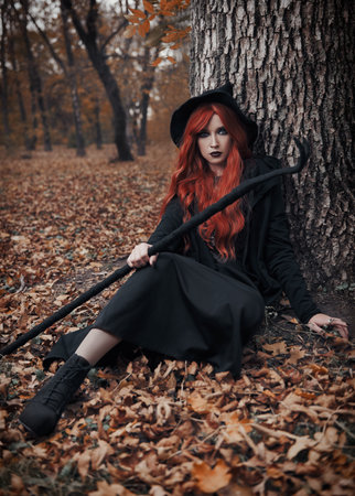 Halloween (Samhain) theme: ginger (red-haired) witch with horned staff sitting at the tree. Portrait...