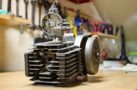 The old engine from little Czech motorbike after renovation with blurred tools in background.
